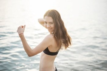 Beautiful woman in black bikini is enjoying with sea water on the beach 