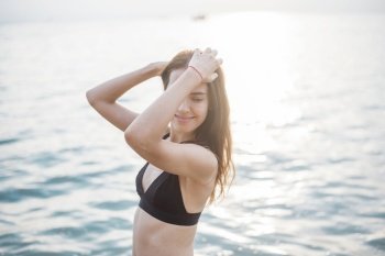Beautiful woman in black bikini is enjoying with sea water on the beach 