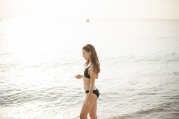 Beautiful woman in black bikini is walking on the beach 