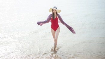 Beautiful woman in red swimsuit is walking from the sea, Summer Concept 