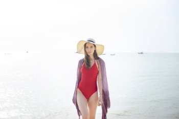Beautiful woman in red swimsuit is walking from the sea, Summer Concept 