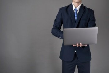 Business man is using laptop ,grey background in studio 