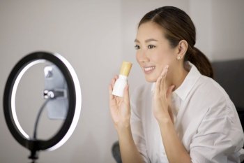 A beautiful Asian makeup blogger is live streaming how to beauty face makeup in her home, beauty and technology concept . . A beautiful Asian makeup blogger is live streaming how to beauty face makeup in her home, beauty and technology concept 
