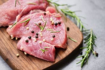 Raw pork meat on wooden cutting board on the kitchen table for cooking pork steak roasted or grilled with ingredients herb and spices , Fresh pork
