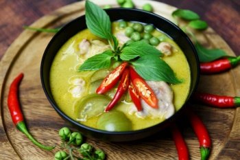 Thai food green curry on soup bowl with ingredient herb vegetable on wooden plate background / green curry chicken cuisine asian food on the table