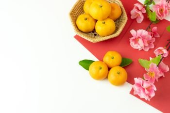 Chinese language mean rich or wealthy and happy.Table top view Lunar New Year & Chinese New Year concept background.Flat lay orange in wood basket & cheery flower with red pocket money on white wooden