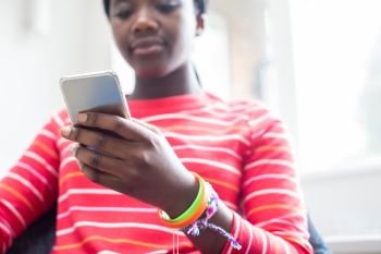 Close Up Of Teenage Girl Wearing Wristbands Using Mobile Phone At Home