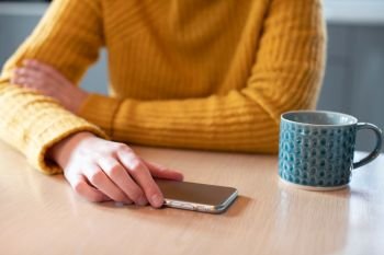 Woman Concerned About Excessive Use Of Social Media Laying Mobile Phone Down On Table