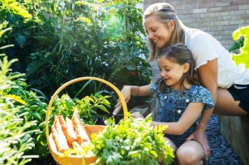 Mother And Daughter Digging In Raised Vegetable Beds At Home