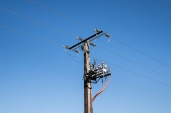 Electrical pylon with high voltage transformer against blue sky.