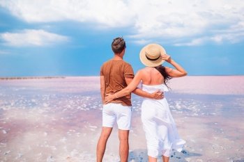 Family vacation. Young couple enjoy beach holiday with amazing view of pink salt lake. Young couple on white beach during summer vacation.