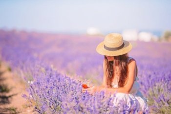 Beautiful young woman on purple flower lavender field. Woman in lavender flowers field at sunset in white dress and hat