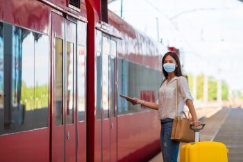 Woman wearing a mask for prevent virus with luggage on the platform travel by aeroexpress. Protection against Coronavirus and gripp. Young tourist woman with baggage on the platform waiting for train