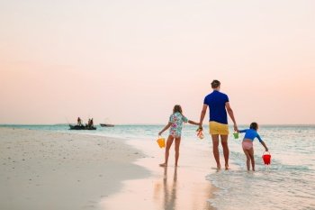Happy father and adorable little kids on tropical beach having fun. Family vacation. Happy father and his adorable little daughters at tropical beach having fun