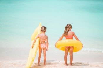Little girls having fun at tropical beach playing together. Adorable little sisters at beach during summer vacation. Little happy funny girls have a lot of fun at tropical beach playing together. Sunny day with rain in the sea