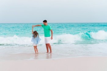 Happy father and his adorable little daughter at white sandy beach. Little girl and happy dad having fun during beach vacation