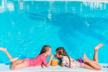Adorable little girls in outdoor swimming pool. Adorable little girls playing in outdoor swimming pool on vacation