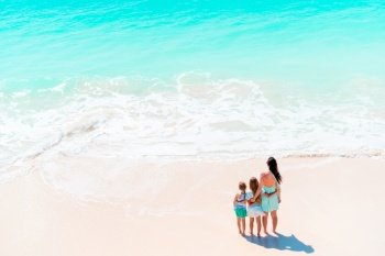 Adorable little girls and young mother on white beach. View to the family on the beach and ocean from above. Beautiful mother and her adorable little daughter at beach