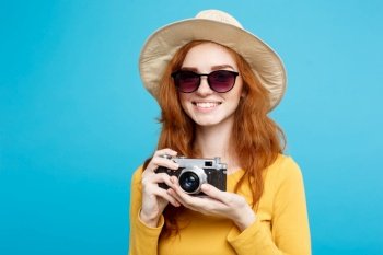 Travel concept - Close up Portrait young beautiful attractive redhair girl with trendy hat ,sunglass and vintage camera smiling to camera. Blue Pastel Background. Copy space.