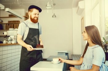 Coffee Business Concept - Waiter or bartender giving chocolate cake and talking with caucasian beautiful lady in blue dress at Coffee shop. Coffee Business Concept - Waiter or bartender giving chocolate cake and talking with caucasian beautiful lady in blue dress at Coffee shop.