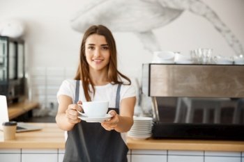 Coffee Business Concept - Caucasian female serving coffee while standing in coffee shop. Focus on female hands placing a cup of coffee.