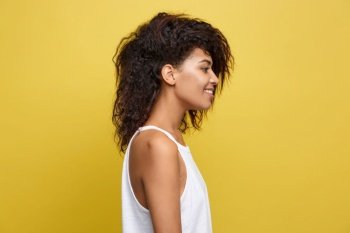 Side view portrait of beautiful attractive African American woman over yellow studio background. Copy Space.. Side view portrait of beautiful attractive African American woman over yellow studio background. Copy Space