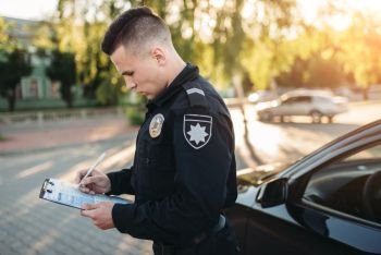 Male police officers in uniform writes a fine on the road. Law protection, car traffic inspector, safety control job. Male police officers writes a fine on the road