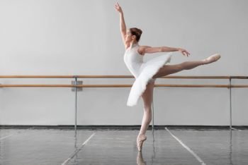 Beautiful female ballet dancer in ballet class, barre and white wall on background. Beautiful female ballet dancer in class