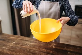 Female person adds cream into a bowl, homemade cake cooking. Fresh tasty dough preparation. Female person adds cream into a bowl, cake cooking