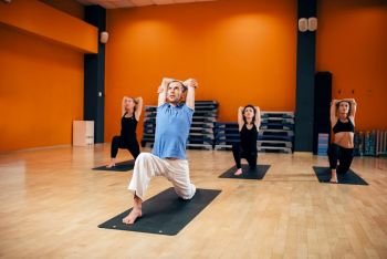 Yoga training class, female group workout with male trainer in gym. Yogi exercise indoor. Yoga training class, female group workout