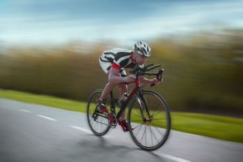 Cyclist in helmet and sportswear rides on bicycle, speed effect, side view. Cyclist rides on bicycle, speed effect, side view