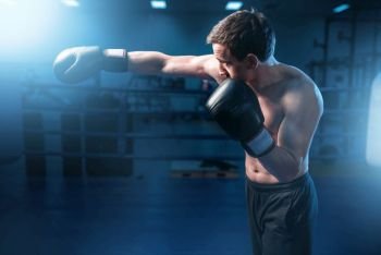 Muscular boxer in black gloves training in gym. Boxing workout, mens sport