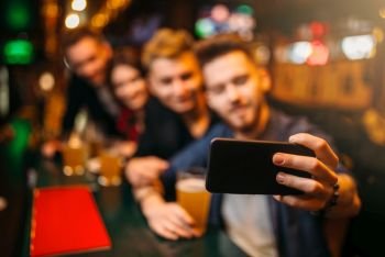 Happy football fans makes selfie on phone camera at the bar counter in a sport pub. Happy football fans makes selfie at bar counter