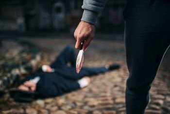 Robber kills his victim with a knife on the night street. Theif commits a robbery attack on a man. Crime concept. Robber kills his victim with knife on night street