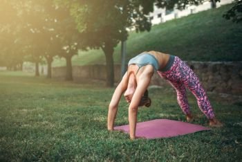 Flexible woman meditating, yoga training on the grass in summer park. Morning yogi meditation. Flexible woman meditating, yoga training