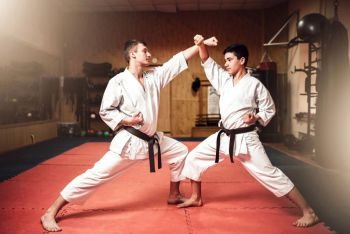 Martial arts masters in white kimono and black belts, self-defence practice in gym. Martial arts masters, self-defence practice in gym