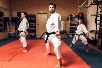Martial arts karate master and his disciples in white uniform and black belts, fight training in action, workout in gym. Martial arts, fight training in action
