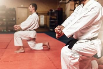 Martial arts karate fighters in white kimono and black belts on workout in gym. Martial arts fighters on workout in gym
