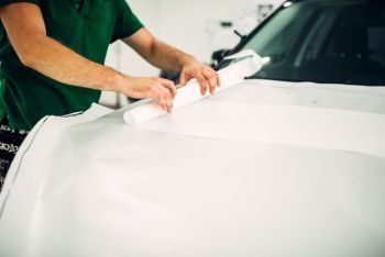 Professional automobile paint protection film installation process. Worker hands prepares protect coating against chips and scratches. Professional automobile paint protection film