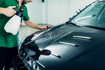 Preparing car, protect against chips and scratches. Worker disperses soapy water. Paint protection. Protective coating. Preparing car, protect against chips and scratches