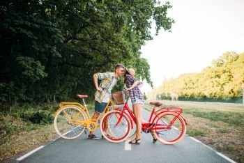 Love couple with vintage bicycle walking in summer park, romantic date of young man and woman. Boyfriend and girlfriend together outdoor, retro bike. Love couple with vintage bicycle walking in park