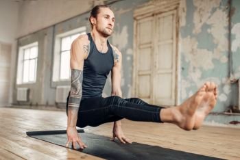 Male yoga standing on hands, balance and press training. Fitness exercise in gym with grunge interior. Fit workout indoors. Yoga standing on hands, balance and press training