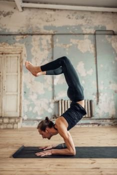 Yoga training on mat in studio with grunge interior. Fit workout indoors, yogi studio, male athlete doing stretching exercise. Yoga training in studio with grunge interior