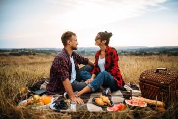 Happy love couple on picnic in summer field. Romantic junket of man and woman. Happy love couple on picnic in summer field