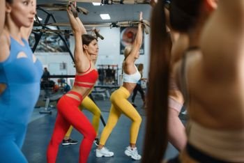 Group of women with slim body doing exercise in gym. People on fitness workout in sport club, athletic girls in sportswear on training indoors. Women with slim body doing exercise in gym