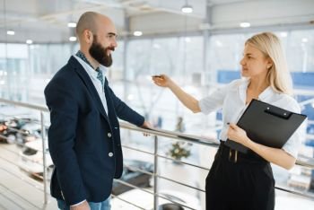 Female seller invites man to presentation in car dealership. Customer and saleswoman in vehicle showroom, male person buying transport, automobile dealer business. Seller invites man to presentation, car dealership