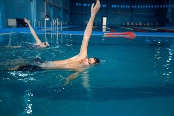 Male swimmer swims in the pool. Man and woman in the water, sport swimming skill training, motion view, workout before competition. Male swimmer swims in the pool