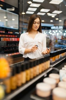 Attractive woman at the shelf in cosmetics store. Buyer at the showcase in luxury beauty shop salon, female customer in fashion market. Attractive woman at the shelf in cosmetics store