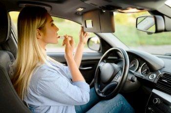 Female student applies makeup in car, lesson in driving school. Man teaching lady to drive vehicle. Driver’s license education. Female student applies makeup, driving school