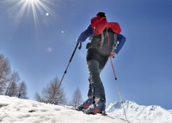 touring skier climbing mountain under sunny blue sky 